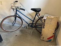 Full side view of blue and silver Free Spirit bicycle showing frame, seat, handlebars and rear box