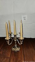 Silver plated zinc WMF 5-arm candle holder with beige wrapped tapered candles seen from front