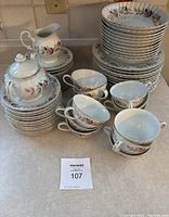 Full set showing stacked medium plates, bowls, and arranged cups with saucers, creamer and sugar bowl.