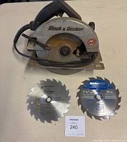 Photo of a Black & Decker circular saw with an attached cord, shown with two additional saw blades in front.
