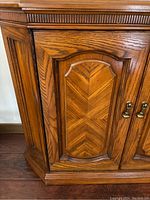 Close-up of one console table door showing fine wood veneer detailing, grain, and beveled paneling.