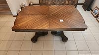 Front view of rectangular wood dining table with decorative top pattern and sturdy pedestal legs.
