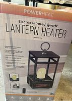 Box showing front view of the PowerHeat Electric Infrared Quartz Lantern Heater including features like supplemental heating for large rooms, adjustable candle brightness and flicker effect, remote control, and decorative black and white quartz rocks.