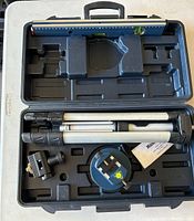 Open view of the carrying case showing the laser level, tripod, and interior compartments.