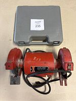 Top view of closed gray plastic carrying case and red Ashland bench grinder with power cord coiled beneath, marked with 'RED' on the main body.