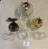 Top-down view of three oil lamps showing metal and glass parts and three separate glass chimneys.
