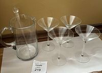 Full set showing clear glass pitcher with stirrer and four clear martini glasses.