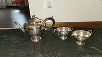Set of three Warren Plate silver plated copper items on black cloth, including teapot, creamer, and sugar bowl
