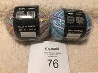 Two balls of Cascade Yarns colorful yarn in variegated pastel colors with labels showing made in Brazil and lot information.