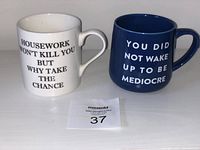 Front view of two large novelty mugs, white with black text and blue with white text
