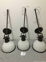 Three historic bronze finish pendant lights with opal glass dome shades displayed side by side, wires visible.