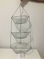 Front view of the 3 tier hanging metal basket organizer, showing all three baskets attached by metal chain with top hook.