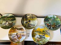 Five duck collector plates arranged in a row showing various duck and natural landscape illustrations, highlighting overall lot contents.