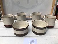 Four Denby mugs and two Denby bowls arranged on a white surface, showing shapes, colors, and glazes.