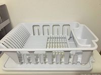 Photo of white plastic dish drying rack showing top and side view, including plate slots and utensil holder compartment.