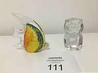 Glass Angel Fish and clear glass Owl paperweights on white surface with auction tag 111