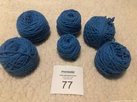 Six balls of light blue yarn of various sizes on beige surface to show lot contents and condition.