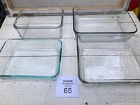 Three clear glass rectangular cooking dishes on white surface, two with Pyrex branding, one without visible brand.