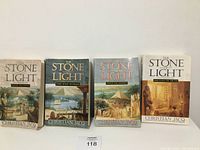 Four paperback books of The Stone of Light series by Christian Jacq aligned side by side showing front covers