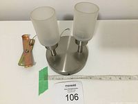 Photo of top view showing round metal base with two frosted glass shades and the mounting bracket included.