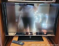 Front view of 32-inch LG LCD TV on stand with remote control placed in front of it.