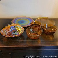 Full view of all seven pieces including candy dish, plates, sunflower dish, and dip bowls showing colors and iridescence