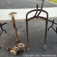 Photo of the metal antique hay fork with lever brake and two pulleys on the table next to it.