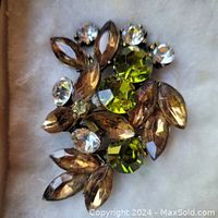 Close-up of vintage rhinestone brooch showing amber marquise, green round, and clear round rhinestones.