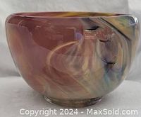 Side view of the blown glass art bowl clearly showing the heavy glass and color pattern in rose, mauve, yellow, and gold hues.