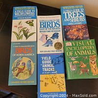 Photo of six field guide books on a wooden floor, showing front covers with titles and illustrations