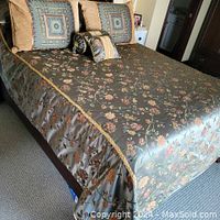 Full view of queen-size bed with reversible floral pattern comforter, braided gold edge, and decorative pillows arranged on top