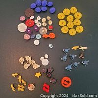 Full lot overview of various colorful vintage plastic buttons arranged by color and shape on dark surface