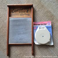 Wooden washboard with zinc scrubbing surface next to packaged 40-foot retractable cord reel