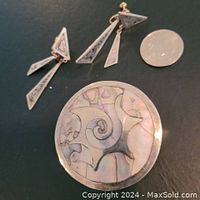 Top view of the large round brooch/pendant with abalone shell inlay along with a coin for scale