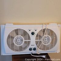 Front view of Helmets twin window fan with control knobs visible and power cord.