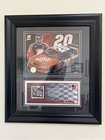 Full frontal image of the framed Tony Stewart collectible with car image and racing memorabilia inside black frame.
