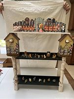 Front view of a wooden decorative curio shelf with birdhouse designs and multiple miniature animal figurines on three shelves against a white backdrop.