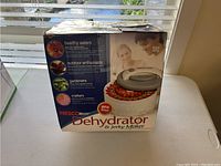 Original packaging for the Nesco Dehydrator and Jerky Maker showing product image and features