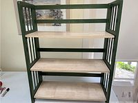 Front view of the 3-tier display shelf showing the green frame and three natural wood shelves.