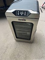 Front angle view of the stainless steel Char-Broil electric smoker showing the digital control panel and glass door with racks inside.