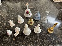 Top view of 10 small collectible bells of various materials including porcelain, glass, and brass with floral decorations and patterns.