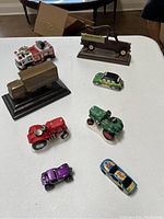 Seven collectible car models displayed on a white surface showing variety of vintage toy cars, models, and die-cast cars.