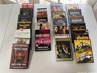 Photo of DVDs and VHS tapes arranged on a white table, showing titles and cover art.