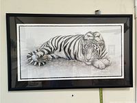 Full view of framed picture depicting a white tiger lying down on a light background.