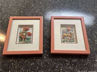 Two framed 3D pictures placed on a dark surface showing detailed nature-themed layered images with cream-colored matting and light brown wooden frames.