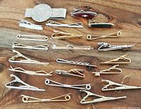 Photo showing all 22 tie clips arranged on a wooden surface in mixed metal finishes and designs