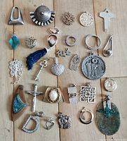 Top-down image showing 28 assorted pendants arranged on a wooden surface to highlight their variety in shapes, materials, and themes.