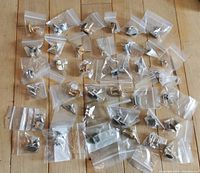 Top-down view of 37 individually bagged cufflink pairs on wooden surface