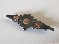 Top view of antique sterling silver brooch with three 10K gold flowers attached, showing engraved details and silver ball accents on edges.