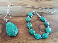 Overview photo of the necklace and bracelet laid on wooden surface, showing stone colors and chain.